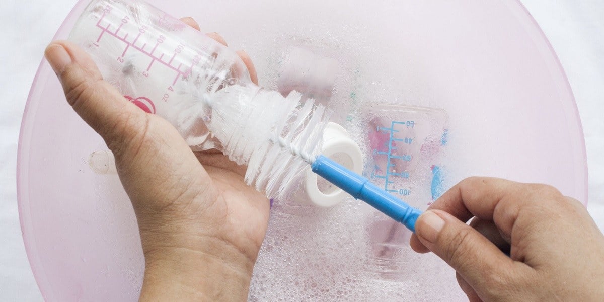 The Complete Guide To Safely Sterilizing Baby Bottles 7 Methods Woman Cleaning Baby Bottles Using A Brush