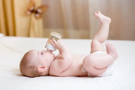 Young baby boy drinking from a glass bottle