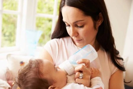 Mother feeding her baby with an anti-colic bottle