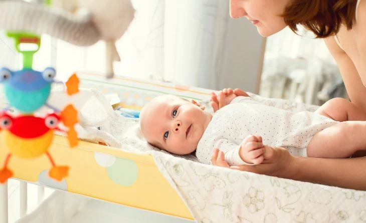 Mother changing baby's diaper on a changing table