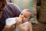 Father feeding bottled milk to breastfed baby girl