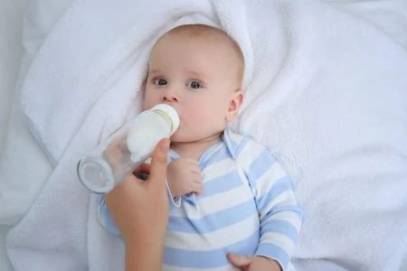 Baby drinking from a warmed milk bottle