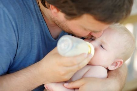Father bottle feeding his son with a sterilized baby bottle
