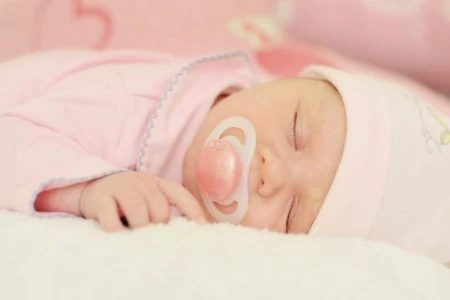 Baby sleeping while soothing on a pacifier