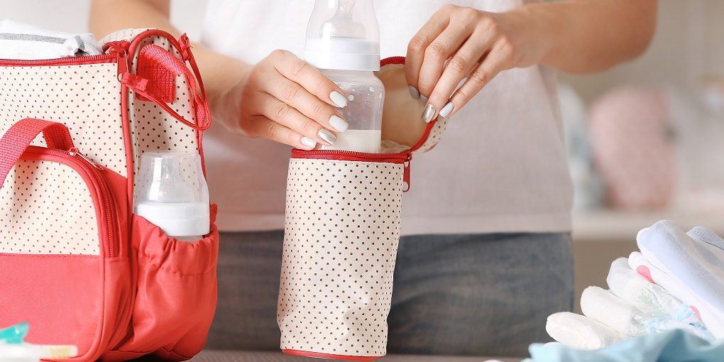 Woman packing her breast pump bag bag with child bottle