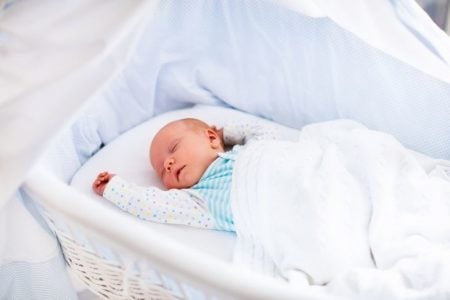 Newborn baby sleeping in a white bassinet