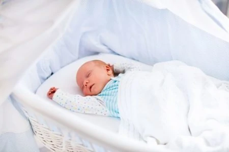 Newborn baby sleeping in a white bassinet