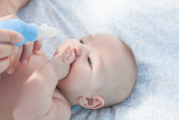 Mother using a nasal aspirator to clean baby's nose
