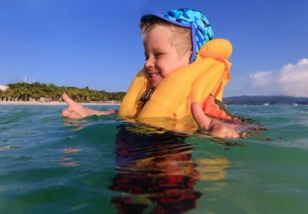 Baby boy wearing a life jacket playing in the ocean water