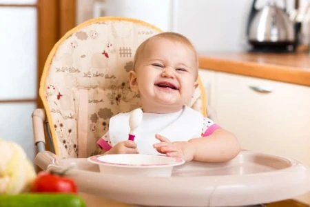 Baby eating in a booster seat in the kitchen