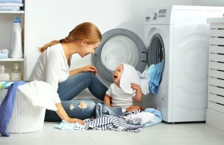 Mother and baby playing with clean laundry