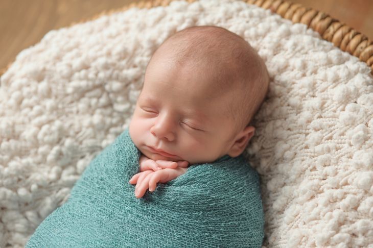 Newborn baby sleeping in swaddle blanket