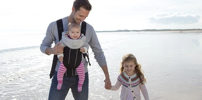 Father babywearing with daughter on the beach
