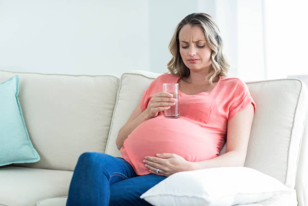 Pregnant woman with dry mouth drinking water