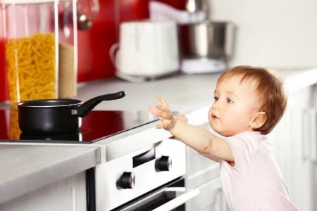 Young child touching a frying pan in the kitchen