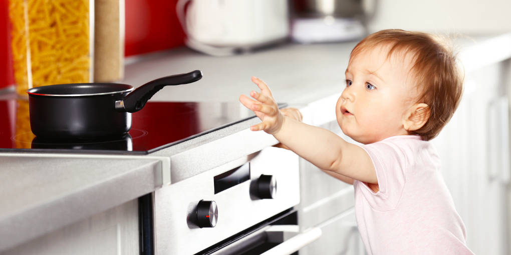 The Ultimate Checklist to Babyproofing Your Home Young child touching a frying pan in the kitchen