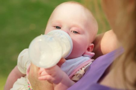 Mother feeding newborn daughter from a bottle