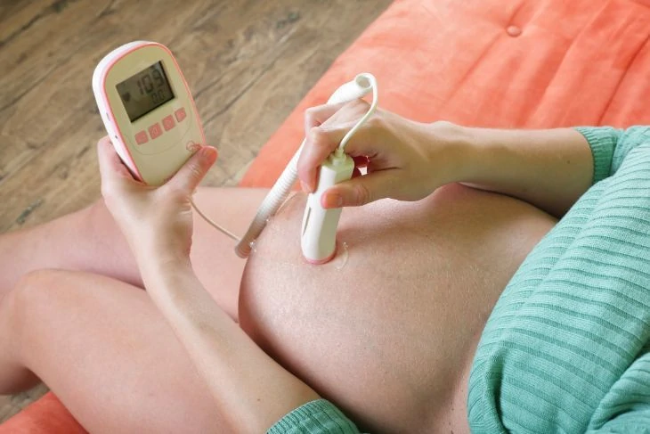 Pregnant woman using a fetal doppler monitor