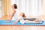 Mother and daughter doing yoga exercises on a mat
