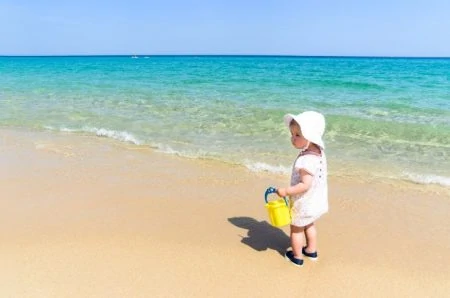 Baby wearing a sun hat on the beach