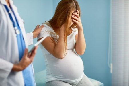 Pregnant woman covering her face at the doctor's clinic