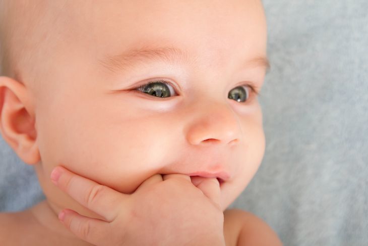 Cute baby chewing on fingers while teething