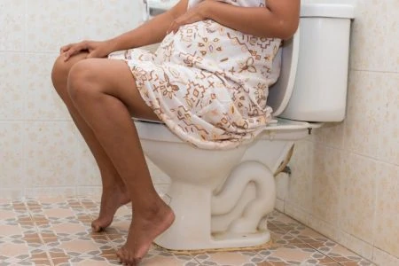 Pregnant woman sitting on the toilet with constipation