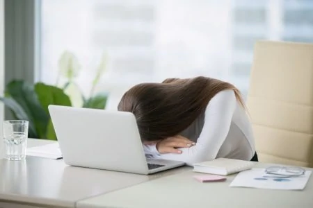 Woman taking a nap on the desk in front of her laptop