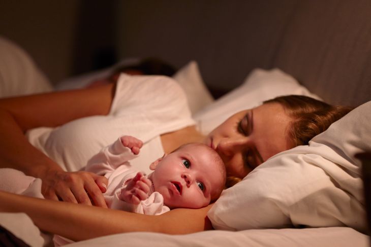 Mom sleeping with baby on the bed