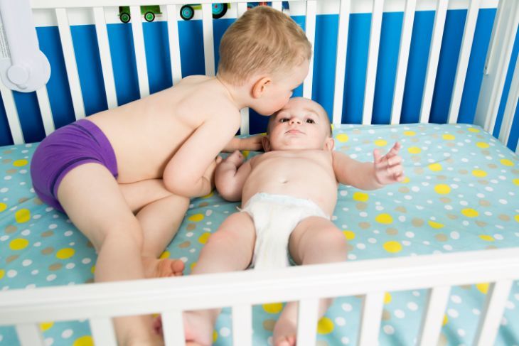 Is My Baby Ready To Sleep In A Crib? Toddler kissing baby brother in crib