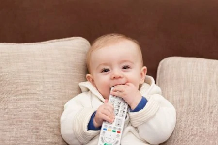 Toddler chewing on a TV remote control