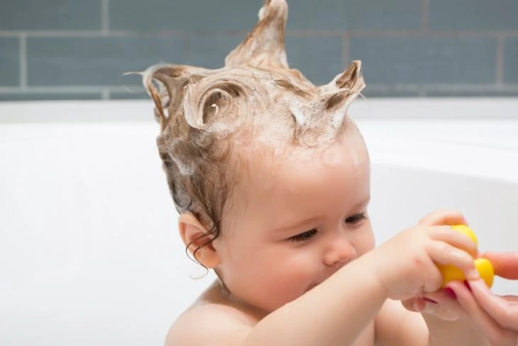 Baby taking a bath with shampoo in hair