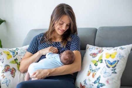 Mother breastfeeding her baby on the sofa