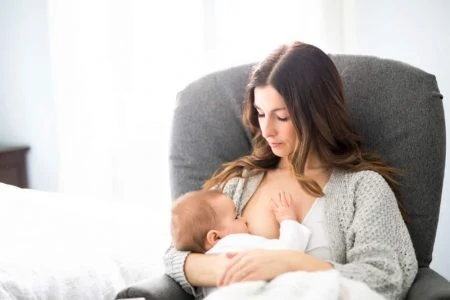 Mother breastfeeding in a glider nursery chair