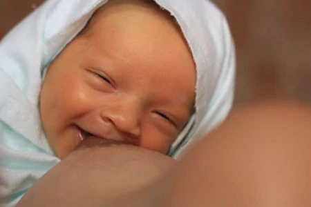 Smiling baby breastfeeding