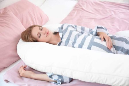 Pregnant woman sleeping with a pregnancy pillow
