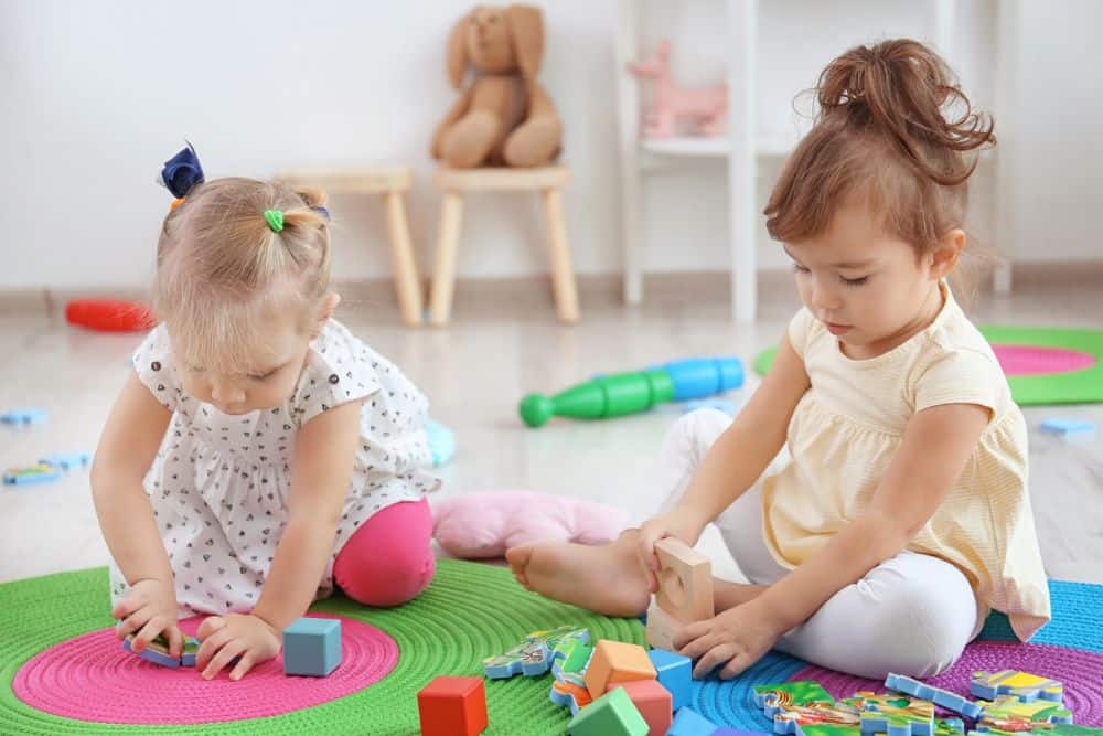 Two toddler girls playing with blocks