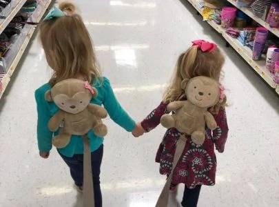 Two toddler girls wearing backpack safety leashes