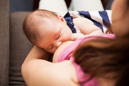 Mother breastfeeding while wearing a nursing top