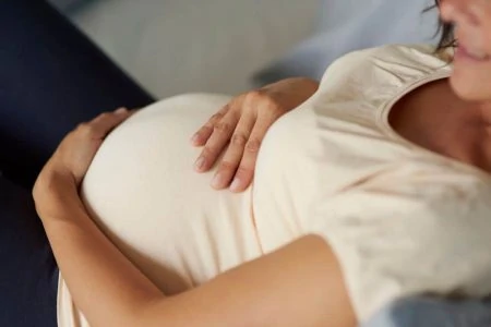 Close up of pregnant woman holding her belly