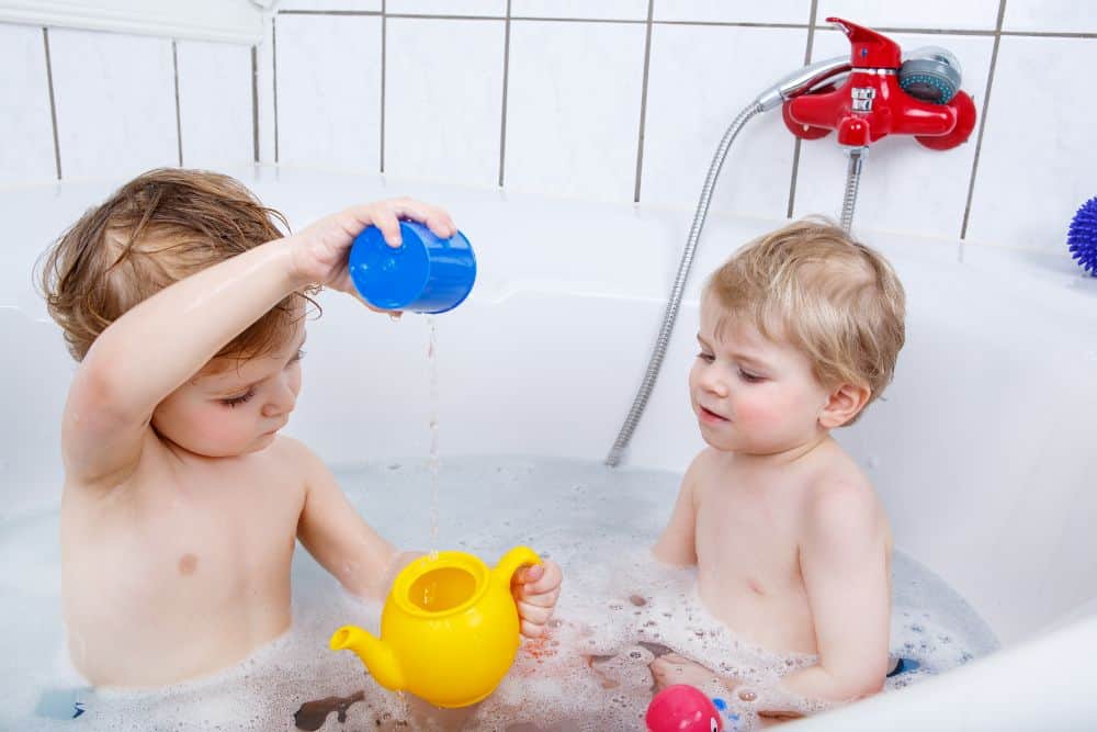 Two toddlers playing in the bathtub