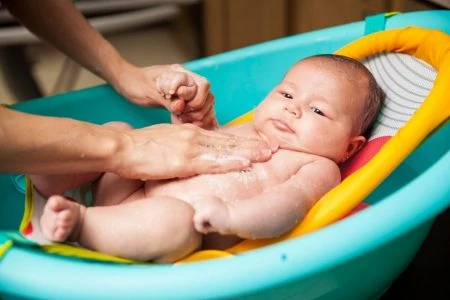 Baby being bathed in a small bath tub