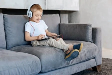 Kid wearing headphones while playing with ipad
