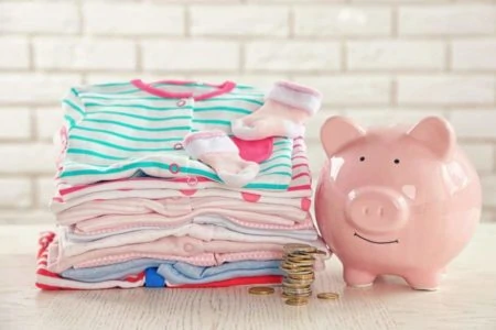 A pile of baby clothes and a piggy bank
