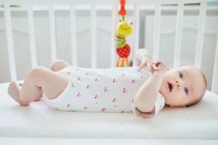 Baby lying on her back in a crib