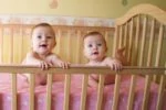 Twin babies lying inside a crib