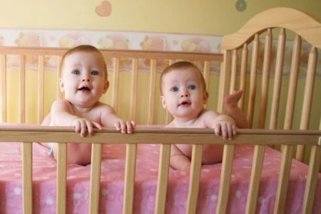Twin babies lying inside a crib