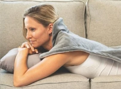 Woman lying on sofa with heating pad on her back