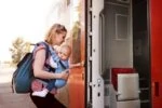 Mom boarding a train while wearing her baby in a carrier