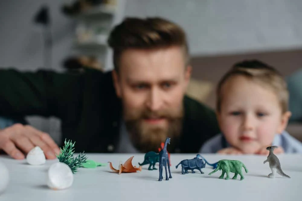 Father and son playing with dinosaur toys